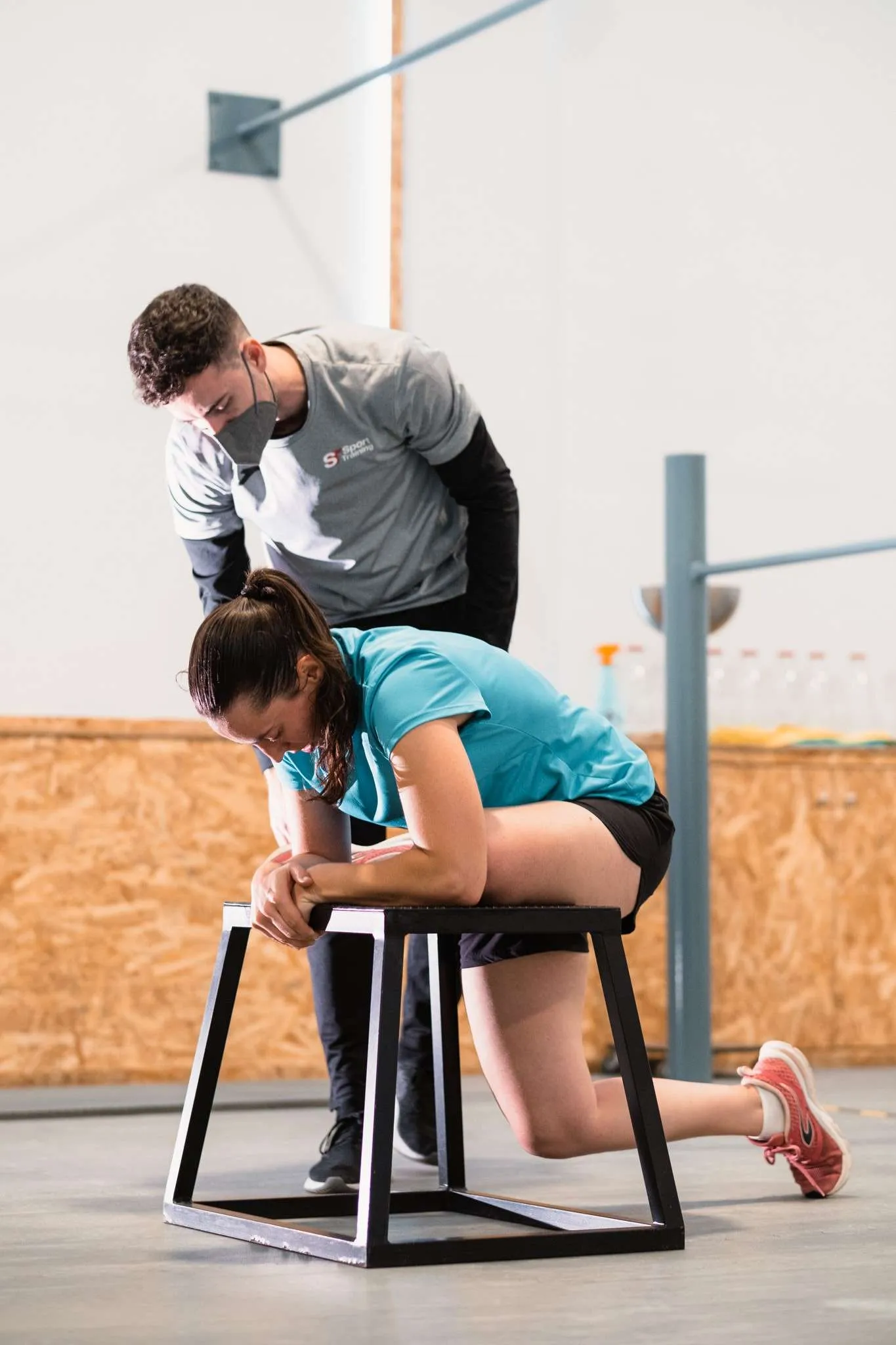 Entrenador Personal Murcia Un entrenador personal ayudando a un hombre y una mujer a realizar sentadillas en un gimnasio de Murcia.